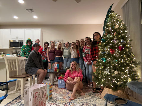 Team gathered around a Christmas tree in a kitchen.